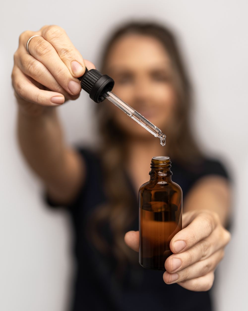 Georgina White holding out an amber bottle and dropper