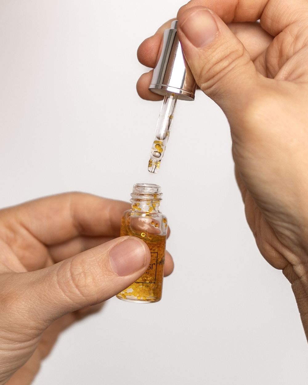 A glass dropper drawing serum from a small bottle