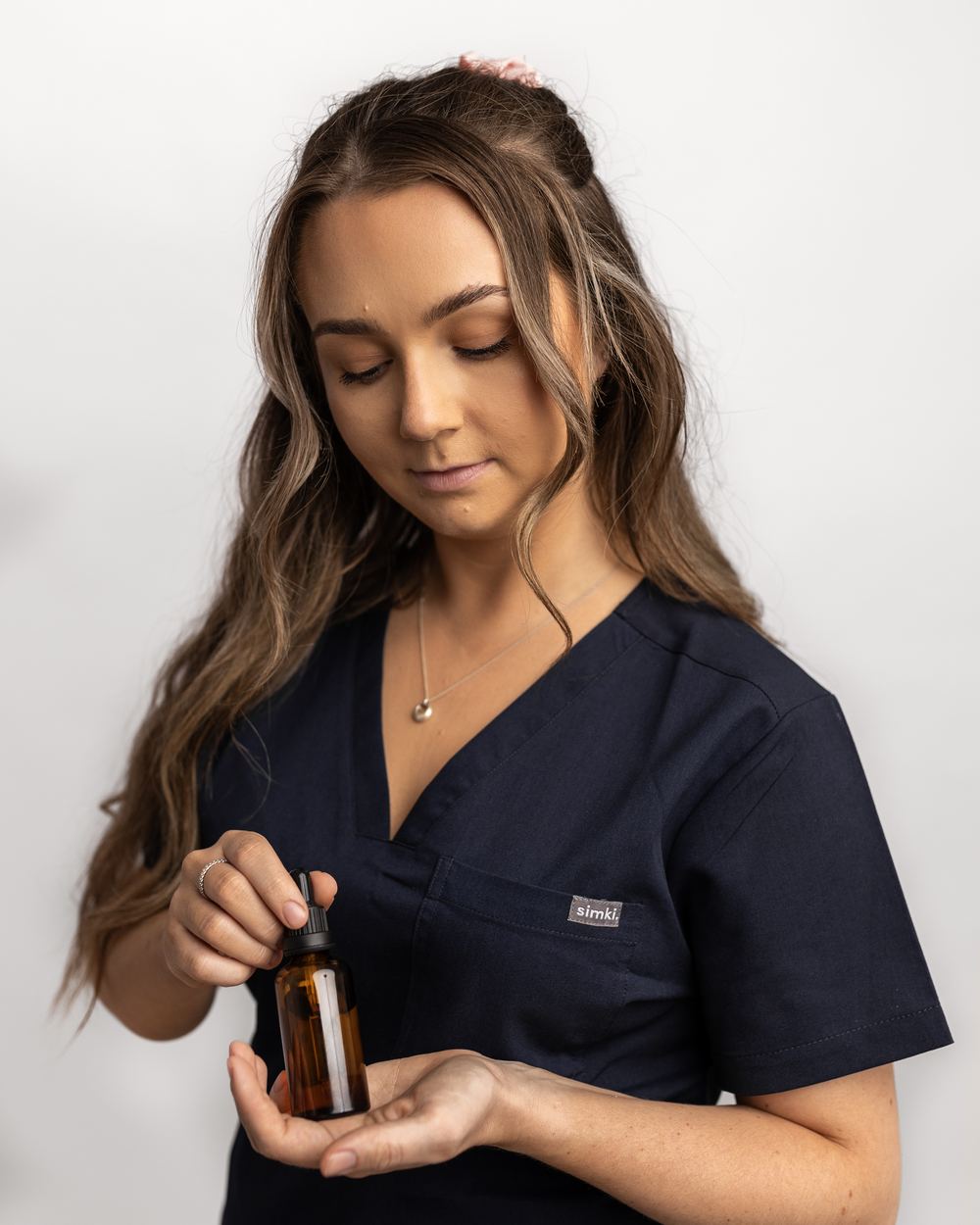 Georgina White holding an amber serum bottle and dropper