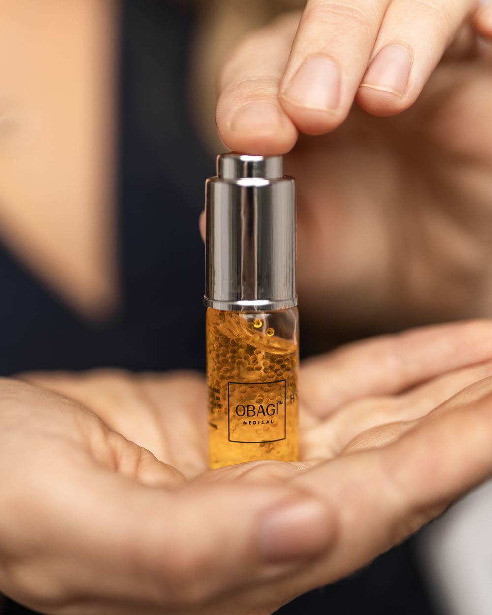 A bottle of golden serum held in an open palm